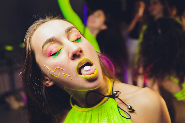 beautiful girl with lsd on tongue in nightclub with pink smoke. - Fotó, kép