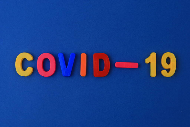 Uma palavra ou texto Covid-19 escrito em um alfabeto infantil com letras clássicas em um ímã. - Foto, Imagem