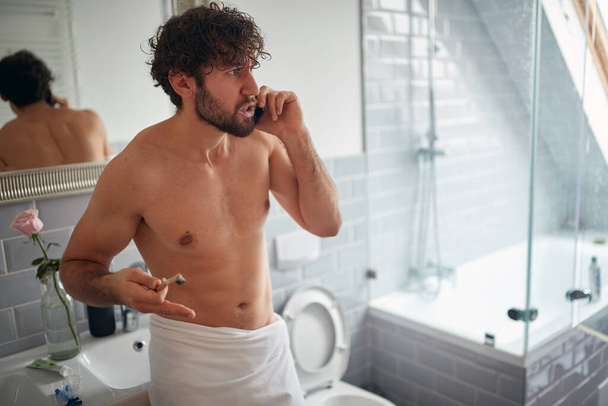 Angry topless man fighting while brushing teeth in the bathroom - Foto, Bild
