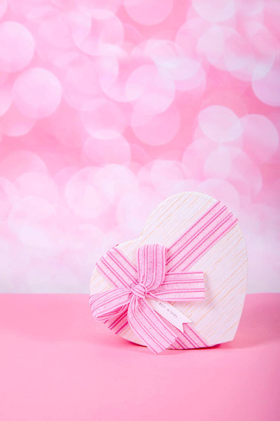 Подарунок з бантом у вигляді серця на рожевому тлі з боке
 - Фото, зображення