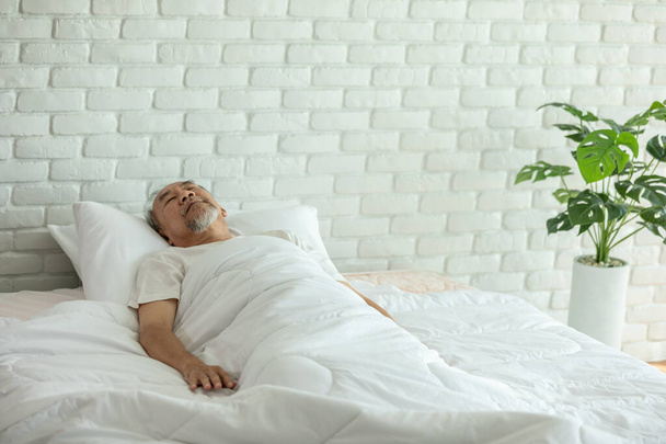 Asian Elderly man close eyes smile sleep and sweet dream on bed in bedroom in the morning feeling so relax and comfortable,Healthcare and Sleep Concept - Fotó, kép