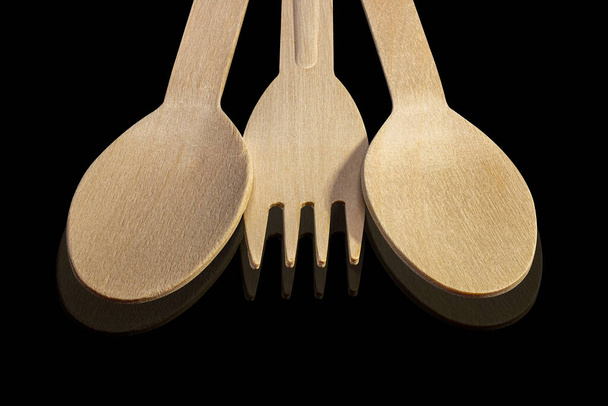 Set di posate in legno. Cucchiai e forchette in legno su fondo nero isolato. Elettrodomestici monouso ecologici. - Foto, immagini