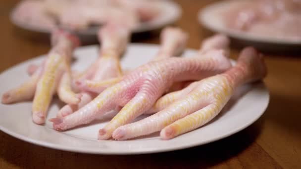 Weibliche Hand legt frische Hühnerpfoten auf einen Teller. Home Kitchen. 4K. Nahaufnahme. - Filmmaterial, Video