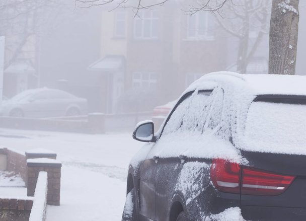 雪の冬の日に暗い車のボディに雪が閉じます. - 写真・画像