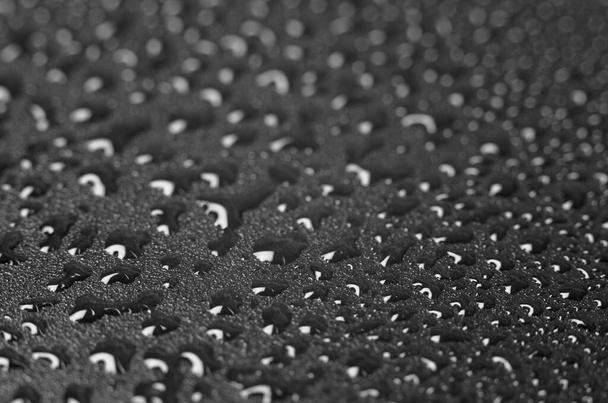 Kristallen druppels water op een zwarte achtergrond. Zwarte achtergrond met waterdruppels, selectieve focus. - Foto, afbeelding