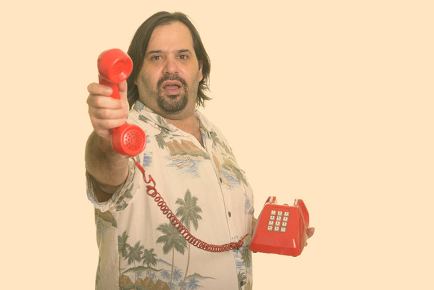 Fat Caucasian man passing call from old telephone - Foto, imagen