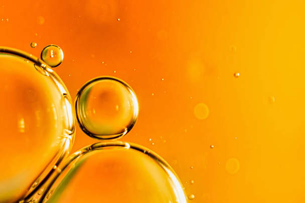 gocce d'olio su acqua su uno sfondo arancione - Foto, immagini