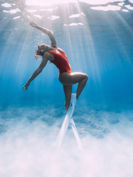 Ελκυστική γυναίκα ελεύθερη δύτης με λευκά πτερύγια ποζάρουν κάτω από το νερό στην τροπική θάλασσα. - Φωτογραφία, εικόνα