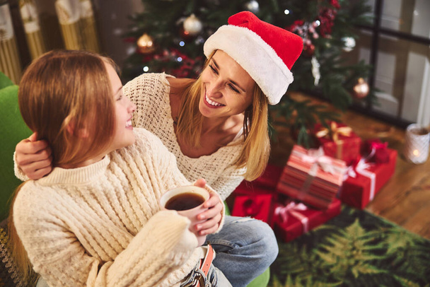 Cheerful mother celebrating Christmas with teenage girl indoors - Foto, Imagen