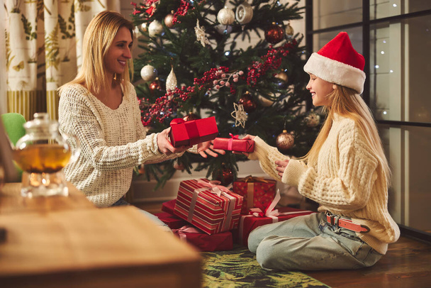Happy girl unwrapping presents with mom at Christmas - Zdjęcie, obraz