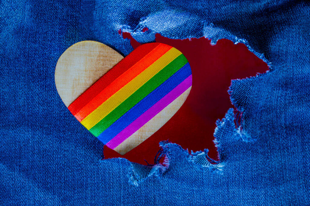 Big heart with LGBT symbols in torn denim trousers on a red background. Love and romance. Declaration of love. Free love. Valentine's Day card. - Photo, Image