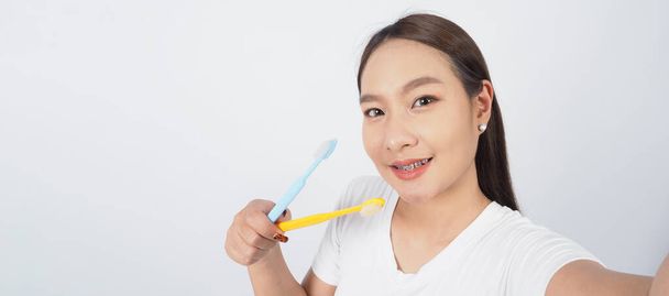 Zęby aparatu. Stomatologia sexy dziewczyna uśmiech trzymając szczoteczkę do zębów i patrząc do kamery. białe zęby z niebieskimi szelkami. Opieka dentystyczna. Azjatka z soczewką kontaktową i ortodontą. Koncepcja opieki ustnej. - Zdjęcie, obraz
