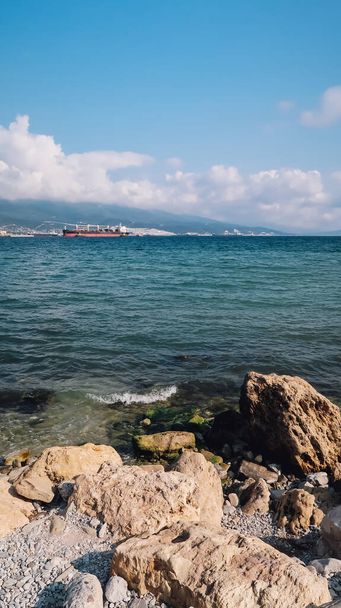NOVOROSSIYSK, RUSSIA - CIRCA SEPTEMBER 2020: view on the Black Sea and big rocks on the shore in the port of Novorossiysk. - Фото, изображение