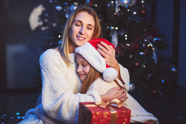 Happy mother hugging beloved daughter at Christmas - Фото, зображення