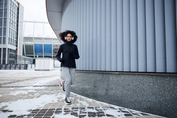 Energetic sportswoman is running along the building - Foto, Imagem