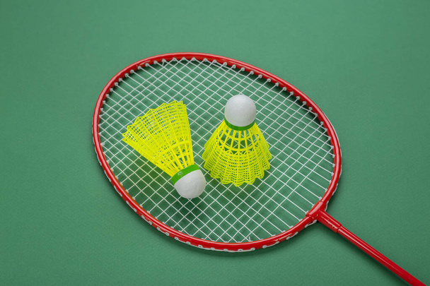 Shuttlecock and racket for playing badminton on a green background. Minimalism. Concept summer entertainment. Sport games - 写真・画像