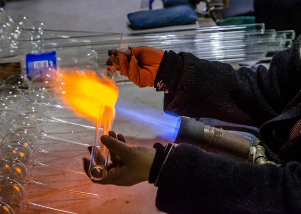glasblazer blaast glazen kogels uit glazen buizen brander met hoge temperatuur propaan vlam - Foto, afbeelding