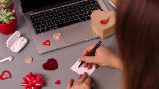 Nuori nainen kirjoittaa kortin Rakastan sinua ja käärimistä Ystävänpäivä lahja - Materiaali, video