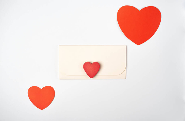 Envelope and red hearts on the light (white) background. Flat lay, top view, space for text. Romantic love letter for Valentine's day concept. - Foto, afbeelding