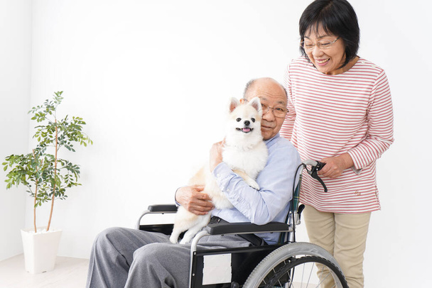 oude vrouw de zorg voor haar man in de rolstoel - Foto, afbeelding