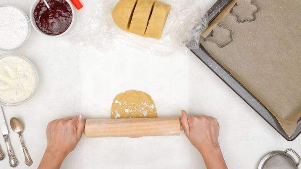 Vrouwelijke handen rollen koekjesdeeg op keukentafel. Shortbread cookie recept, stap voor stap bakproces - Foto, afbeelding