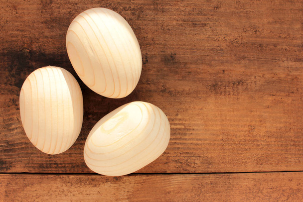 Huevos de Pascua de madera en blanco para pintar o decoupage sobre fondo de madera. Vista superior, espacio de copia - Foto, imagen