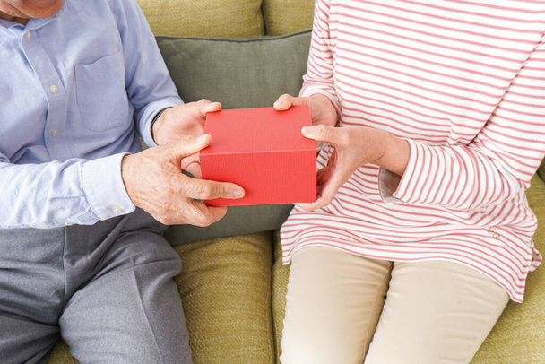  старшая пара, держащая вместе красную коробку  - Фото, изображение