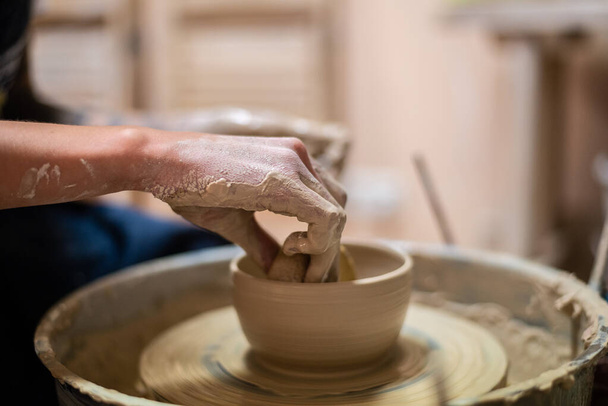 Ceramista femminile che lavora su argilla sulla ruota di un vasaio, mani vicine. Fare una pentola di argilla fatta a mano in laboratorio. Lezione di ceramica, hobby. - Foto, immagini