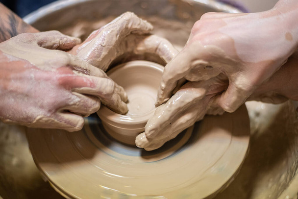 Potier femelle travaillant sur l'argile sur une roue de potier, les mains ferment. Fabrication d'un pot en argile fait à la main dans l'atelier. Leçon de poterie, passe temps. - Photo, image