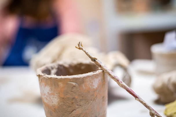 Potier femelle travaillant sur l'argile sur une roue de potier, les mains ferment. Fabrication d'un pot en argile fait à la main dans l'atelier. Leçon de poterie, passe temps. - Photo, image