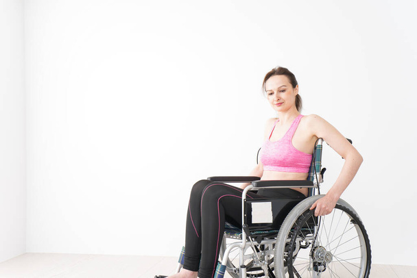 Młoda kobieta na wózku inwalidzkim ubrana w odzież sportową - Zdjęcie, obraz