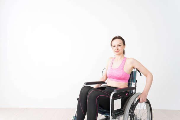 Jeune femme en fauteuil roulant portant des vêtements de sport - Photo, image