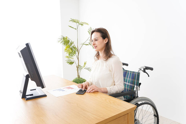 Nuori nainen tekee toimistotyötä pyörätuolissa - Valokuva, kuva