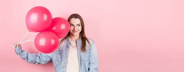 Young caucasian woman holding balloons with happy expression and celebrating a Valentine's day isolated over a pink background - Foto, Imagen