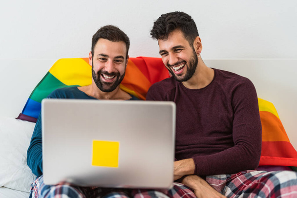 Feliz pareja de hombres homosexuales usando portátil en la cama - Amor homosexual e igualdad de género en el concepto de relación - Foto, Imagen