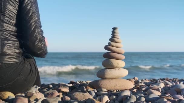 A lány egy kőből készült piramist rak - Felvétel, videó