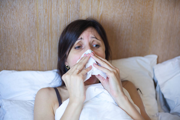 Meisje in bed, sinuspijn, sinusdruk, sinusitis. Droevige vrouw die haar neus en hoofd vasthoudt omdat sinus pijn doet. Sinuspijn die zeer schilderachtige hoofdpijn veroorzaakt. - Foto, afbeelding