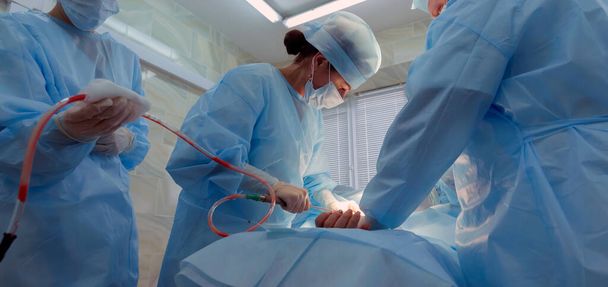 een cosmetische liposuctie operatie in een echte operatiekamer - Foto, afbeelding