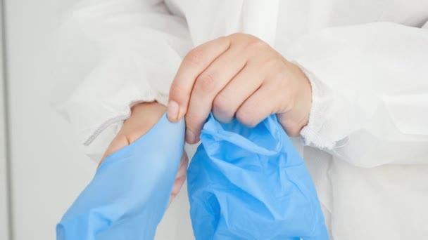 Κλείσιμο ιατρού με προστατευτική στολή βιολογικού κινδύνου που φοράει και φοράει προστατευτικά μπλε λαστιχένια γάντια στο νοσοκομείο - Πλάνα, βίντεο