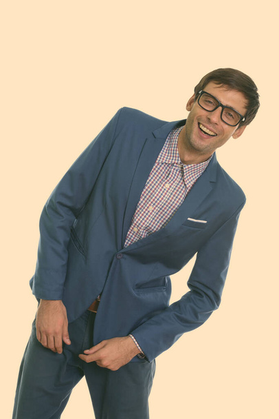 Estudio de tiro de joven hombre de negocios feliz sonriendo y posando mientras lleva gafas - Foto, Imagen