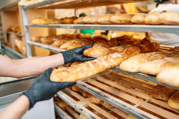 selective focus of baker shelving freshly baked bread - Fotoğraf, Görsel