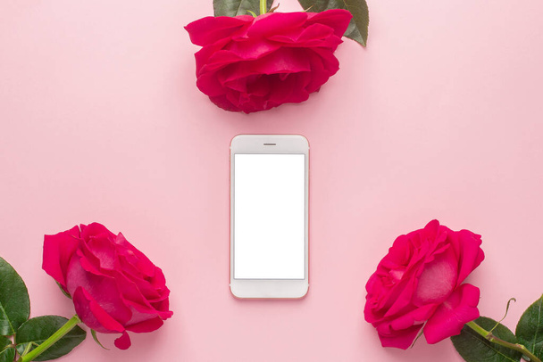 Mobile phone and dark pink rose on a pink background top view - Photo, Image