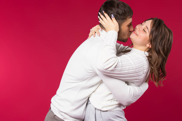 Young couple have fun hugging and fooling around on red background with blank side space. High quality photo - Φωτογραφία, εικόνα