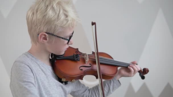 Chlapec blond s brýlemi se učí hrát na housle v hudební škole - Záběry, video