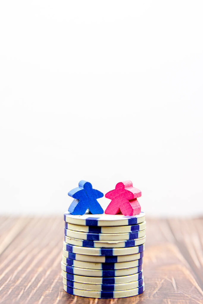 Gender pay equality concept. Blauwe pop die een man en roze pop voorstelt die een vrouw vertegenwoordigen op een stapel munten. - Foto, afbeelding