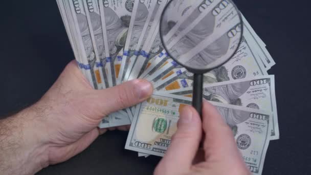Person checking dollar banknote for authenticity with magnifying glass, close up. - Footage, Video
