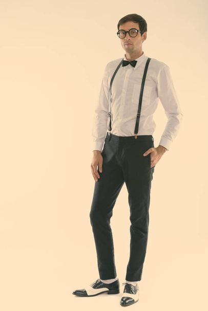 Full body shot of young handsome man standing while wearing suspenders and bow tie - Foto, imagen