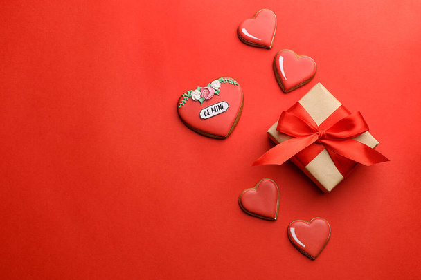 Gift box and heart shaped cookies on red background - Fotó, kép