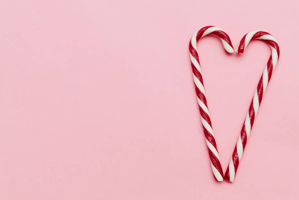 Dos bastones de caramelo formando una forma de corazón, sobre fondo rosa con espacio para copiar. Concepto de San Valentín. - Foto, Imagen