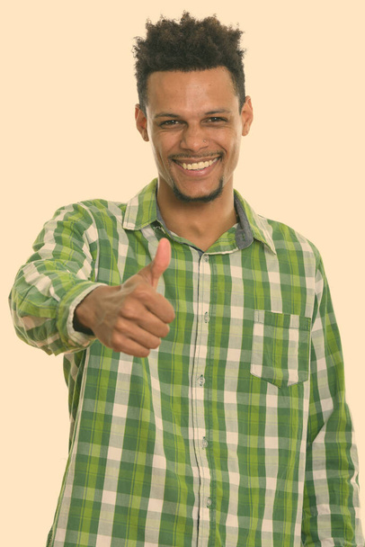 Studio shot of young happy African man smiling while giving thumb up - Foto, imagen